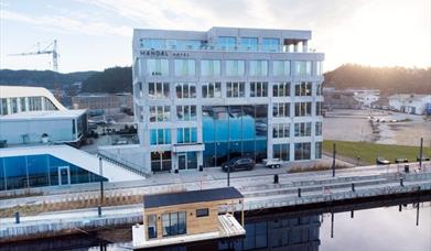 Oversiktsbilde av Mandal Hotel og badstubåten Pysen som ligger i Mandalselva
