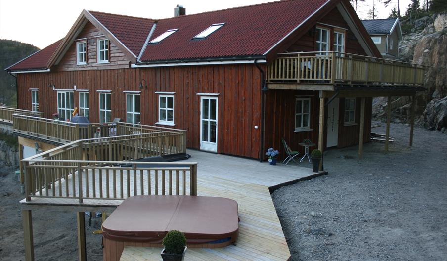 Brun hytte med balkong og terasse. Jacuzzi boblebad på terrassen.