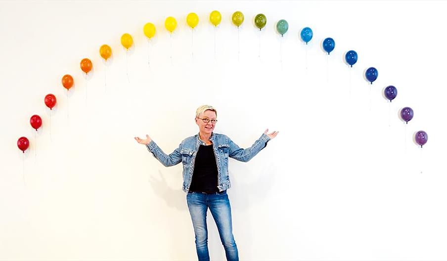 Blid dame under fargerik regnbue ballong