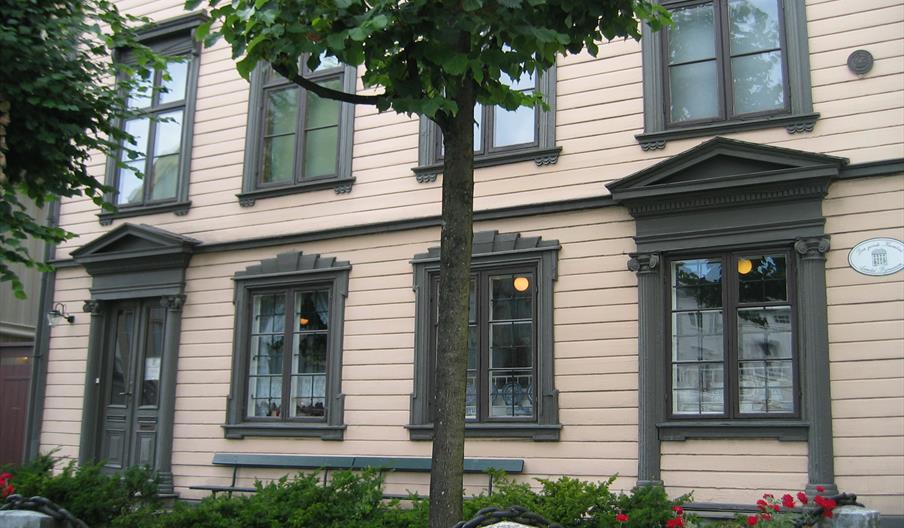 fasade på Kløckers hus - Arendal bymuseum. Beige med mørkegrønne lister rundt vinduene.
