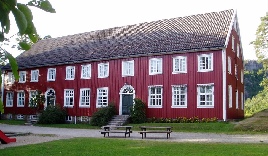 Høgtun Kultursenter, stort rødt bygning med hvite karmer. 20 vinduer på en vegg + 2 dører.