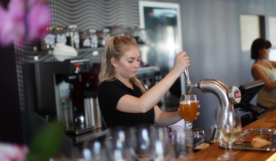 En ansatt som tapper øl i et glass