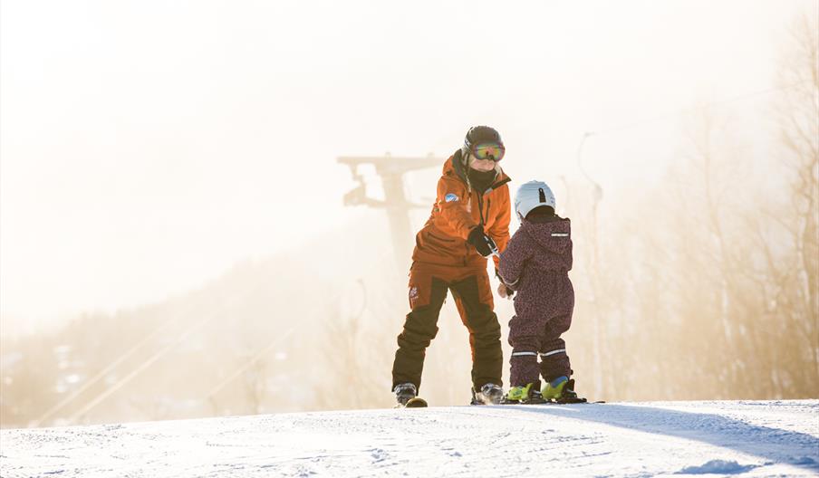 Barn med instruktør på skiskole, bilde