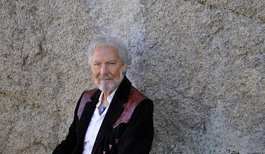 Countryartist Arne Benoni i mørk jakke foran en steinvegg.