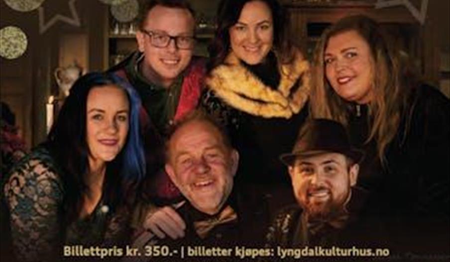 Gruppebilde av artistene bak Nissenes julekonsert, smilende i julepyntet miljø.