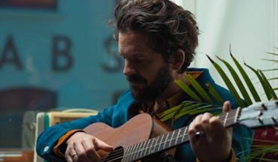 Thomas Dybdahl spiller gitar i et stemningsfullt portrett.