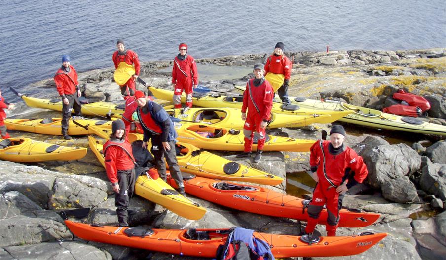 Wannado padlekurs med mange gule og oransje kajakker og padlere på svaberg