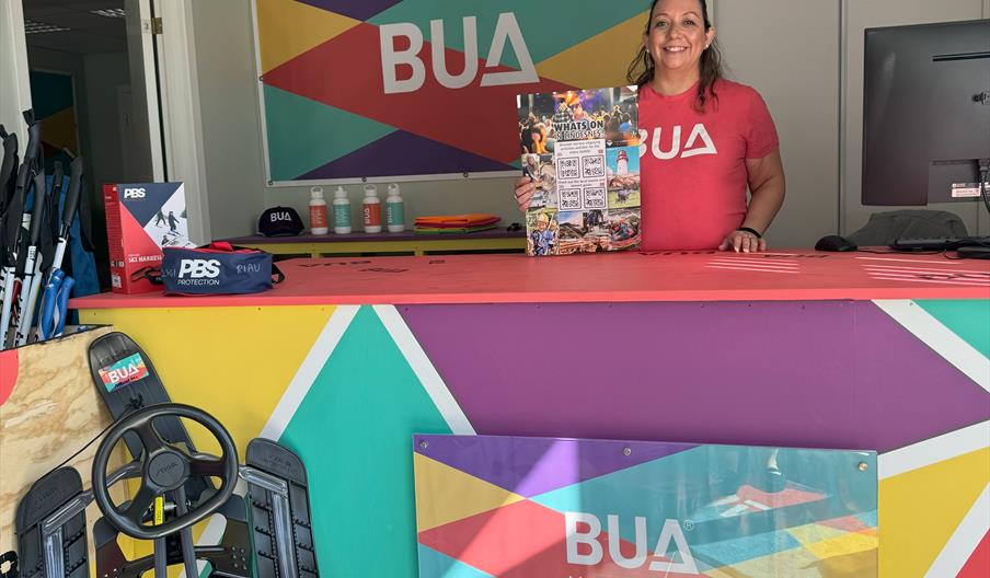 Smilende ansatt på BUA Marnardal, som står bak disken