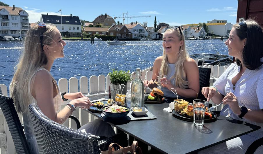 Tre jenter som smiler og spiser god mat hos Brygga