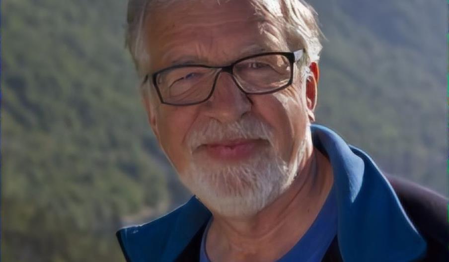Portrett av Oddgeir Bruaset foran grønnkledde fjellsider.