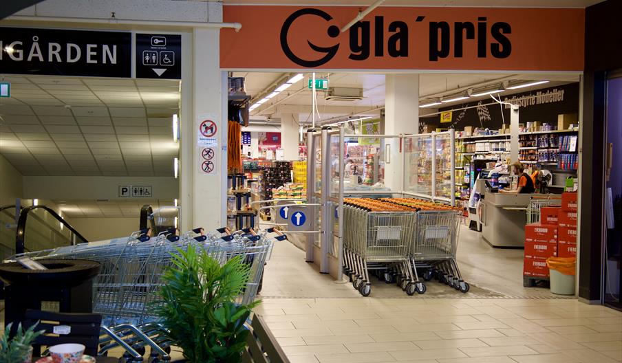 Inngangen til gla’pris Lyngdal i Meierigården, med handlevogner og butikkinteriør.