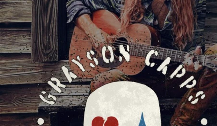 trubadur Grayson Capps fra USA med cowboy hatt og boots og kassegitar ittende på trapp utenfor et stabbur