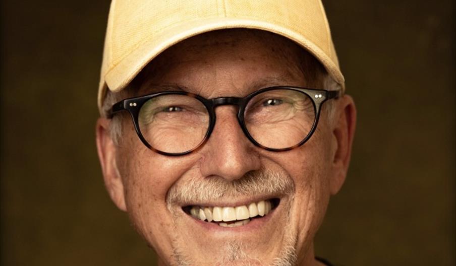 artist Hans Inge Fagervik med gul caps og svarte runde briller som smiler mot kamera.