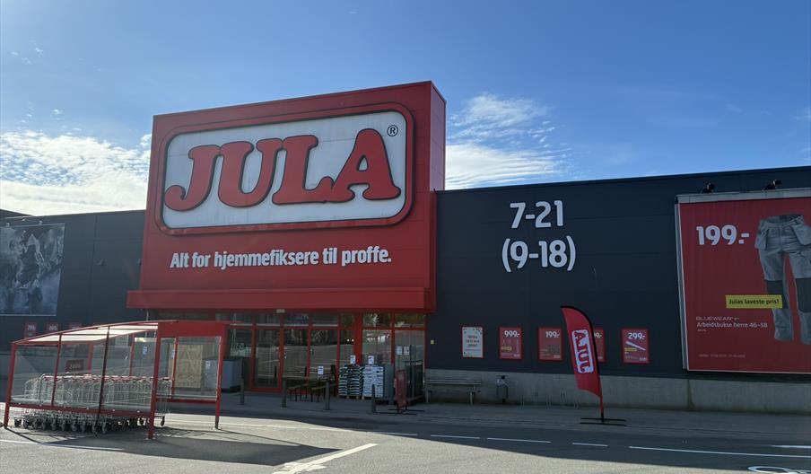 Inngangen til Jula Lyngdal i Handelsparken, med rød logo, handlevogner og åpningstider på fasaden.