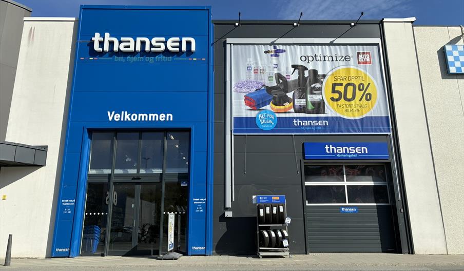 Inngangen til thansen Lyngdal i Handelsparken, med blå fasade og reklamebanner.