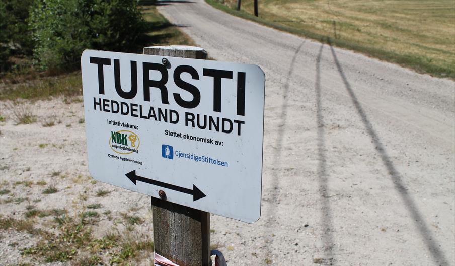 Bilde av skilt "Tursti, Heddeland rundt. Initiativtakere: NBK norges bygdekvinnelag. Øyslebø bygdekvinnelag. Støttet økonomisk av: GjensidigeStiftelsen."
