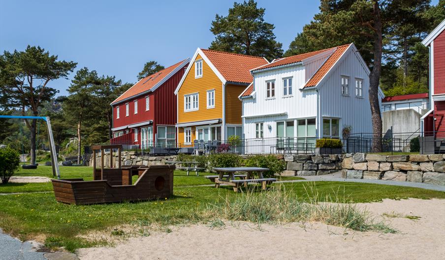 Lekeplass foran et rødt, et gult og et hvitt hus på Furuholmen