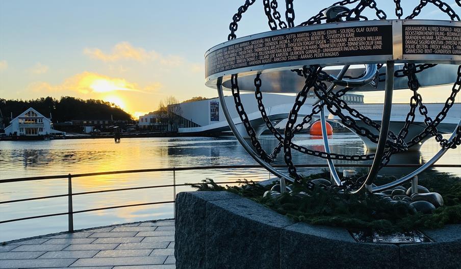 Krigsseilermonumentet i Mandal, med Buen kulturhus og elva i bakgrunnen