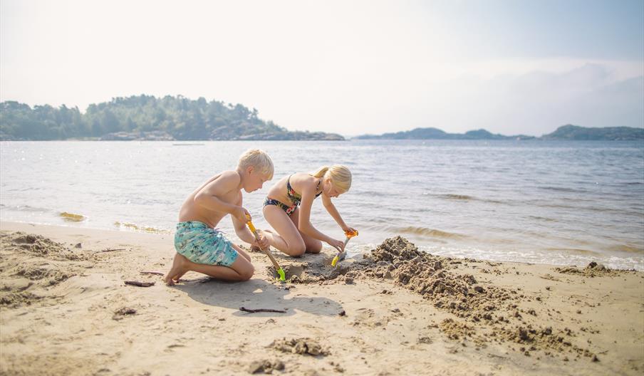 To barn som lager sandslott på stranden