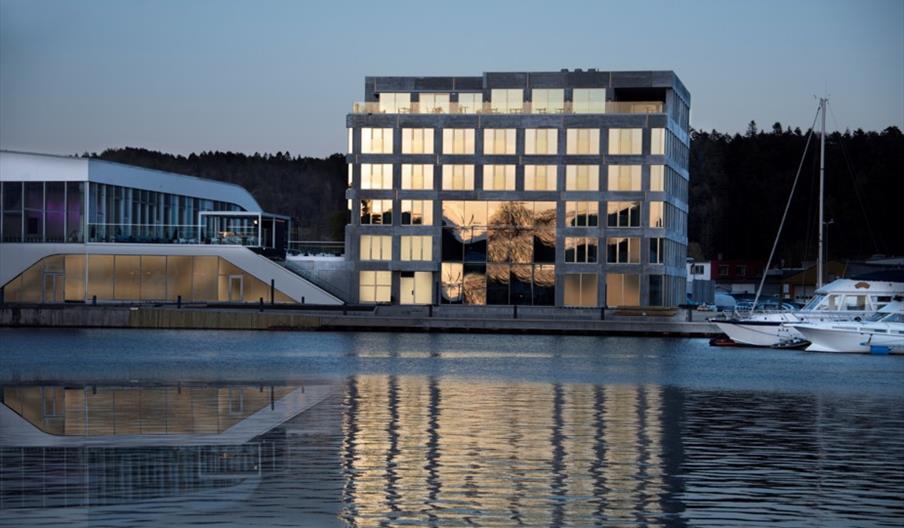 Fasade Mandal Hotel, som speiler seg i Mandalselva ved siden av Buen Kulturhus