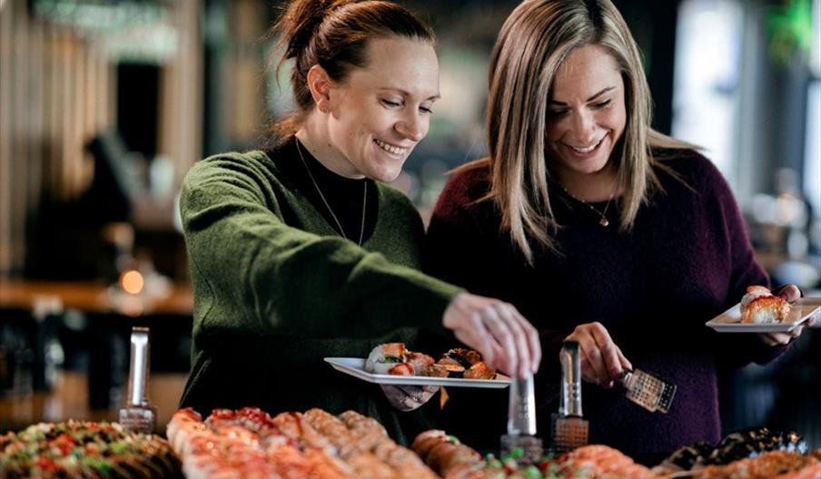 Smilende gjester som forskyner seg av sushi