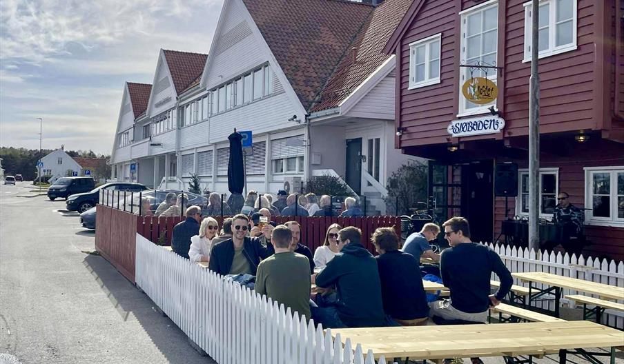 Mennesker som koser seg på uteserveringen foran Sjøboden Pub i Mandal