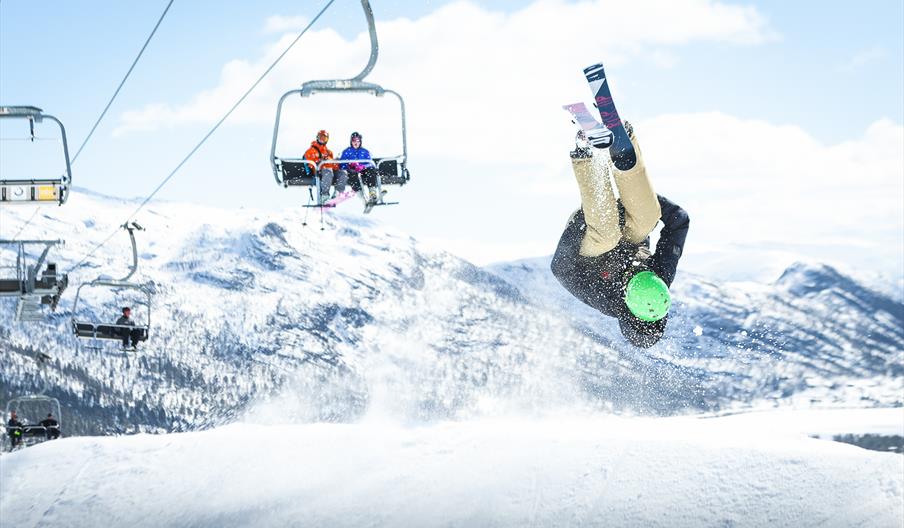 Gutt med ski tar salto i terrengparken, bilde