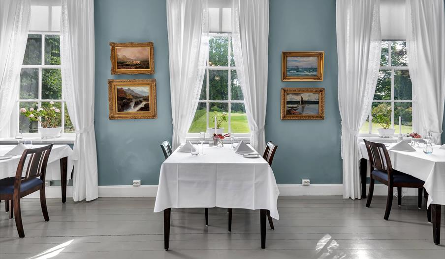rom med blå vegger og hvite gardiner, med spisebord