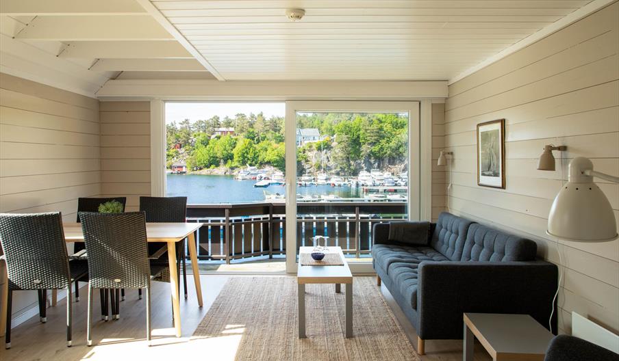 stue med sofa og spisebord og utsikt til sjøen