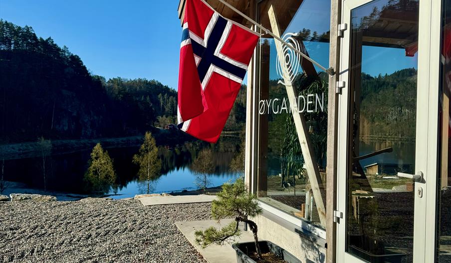 Fasade Øygarden Gård, med flagg i flaggstanga og utsikt ut til vannet