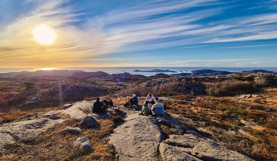 En gjeng som sitter på fjellet, med utsikt ut over havet