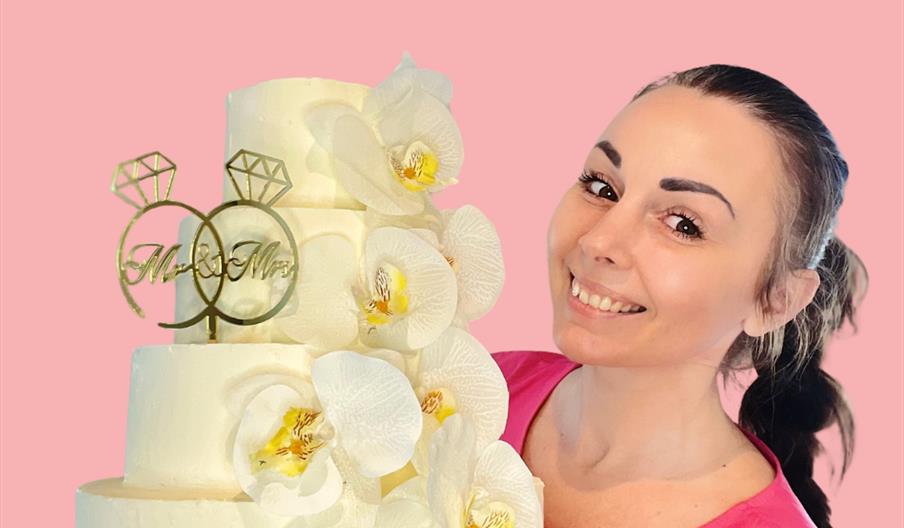 Kvinne som holder en hvit bryllups kake  med blomster detaljer