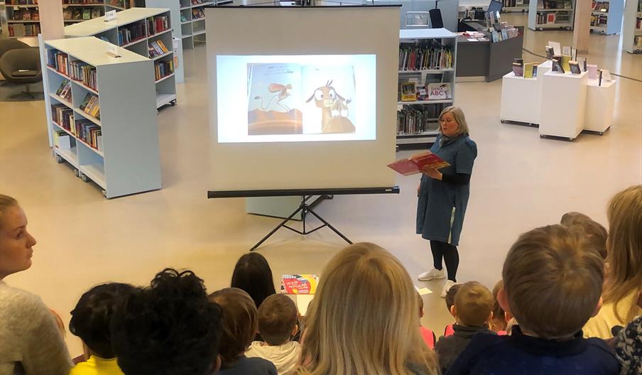 Barn sittende i et amfi, og som følger med på en høytlesning.