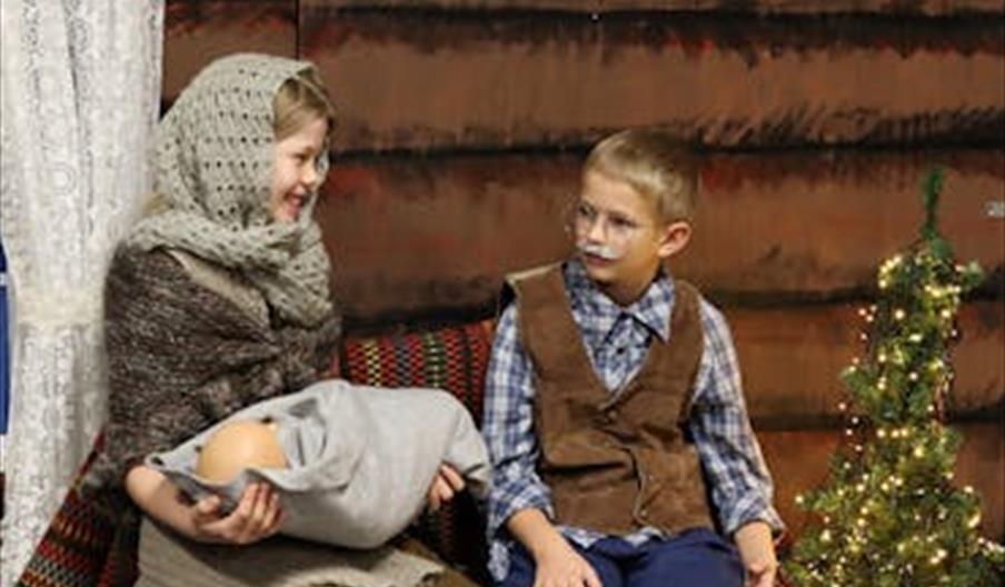 Barn som spiller i skoleforestillingen Papa Panovs juledag – en gutt utkledd som Papa Panov og en jente med babydukke i fanget.