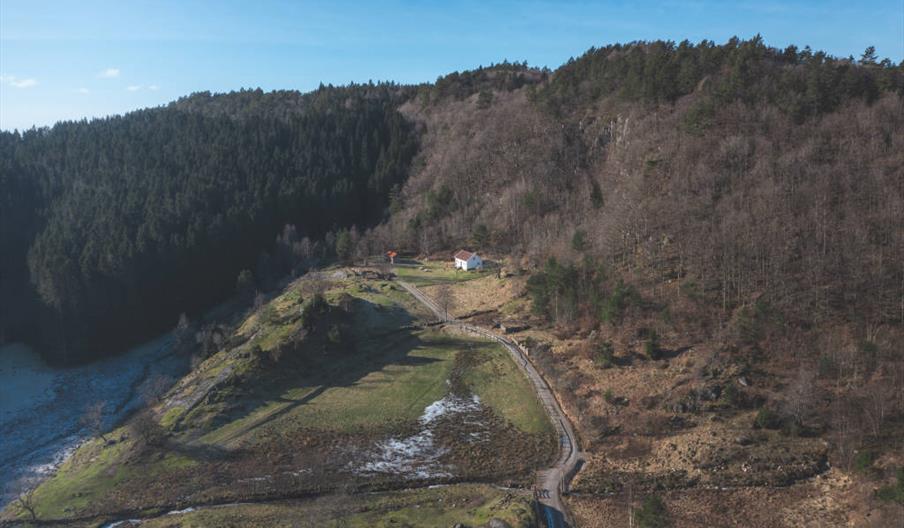 Utsikt over skog og natur på Tjortedal, med DNT hytta midt i bildet