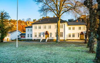 Hald Sommerhotell, en stor grønn flekk foran den hvite bygningen med mange vinduer,