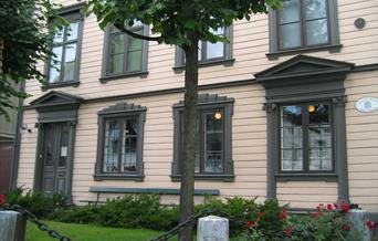 fasade på Kløckers hus - Arendal bymuseum. Beige med mørkegrønne lister rundt vinduene.