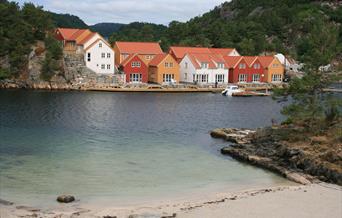 Moderne feriehus i forskjellige farger ved havet, I forgrunnen er en strand.