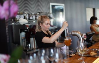 En ansatt som tapper øl i et glass