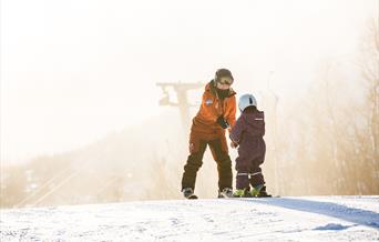 Barn med instruktør på skiskole, bilde