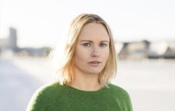 Portrett av forfatter Ida Gilbert i grønn genser utendørs.