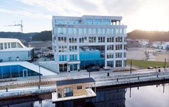Oversiktsbilde av Mandal Hotel og badstubåten Pysen som ligger i Mandalselva