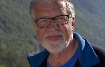 Portrett av Oddgeir Bruaset foran grønnkledde fjellsider.