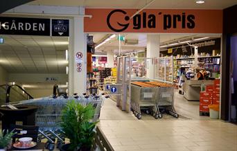 Inngangen til gla’pris Lyngdal i Meierigården, med handlevogner og butikkinteriør.