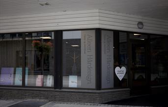 Fasaden til Alleen Hårdesign i Lyngdal sentrum, med store vinduer og tydelig skilt ut mot gata.