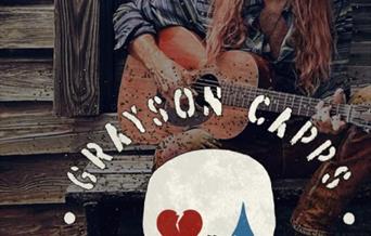 trubadur Grayson Capps fra USA med cowboy hatt og boots og kassegitar ittende på trapp utenfor et stabbur