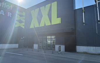 Fasaden til XXL Lyngdal i Handelsparken, med grønn logo på svart bygg.