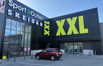 Fasaden til Sport Outlet Lyngdal i Handelsparken, med skilt og store vinduer.