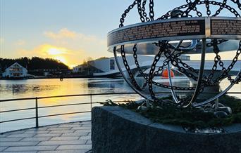 Krigsseilermonumentet i Mandal, med Buen kulturhus og elva i bakgrunnen