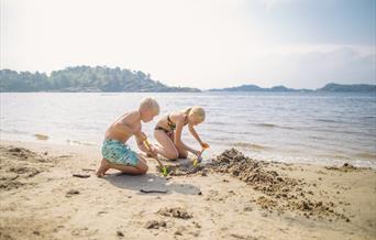 To barn som lager sandslott på stranden